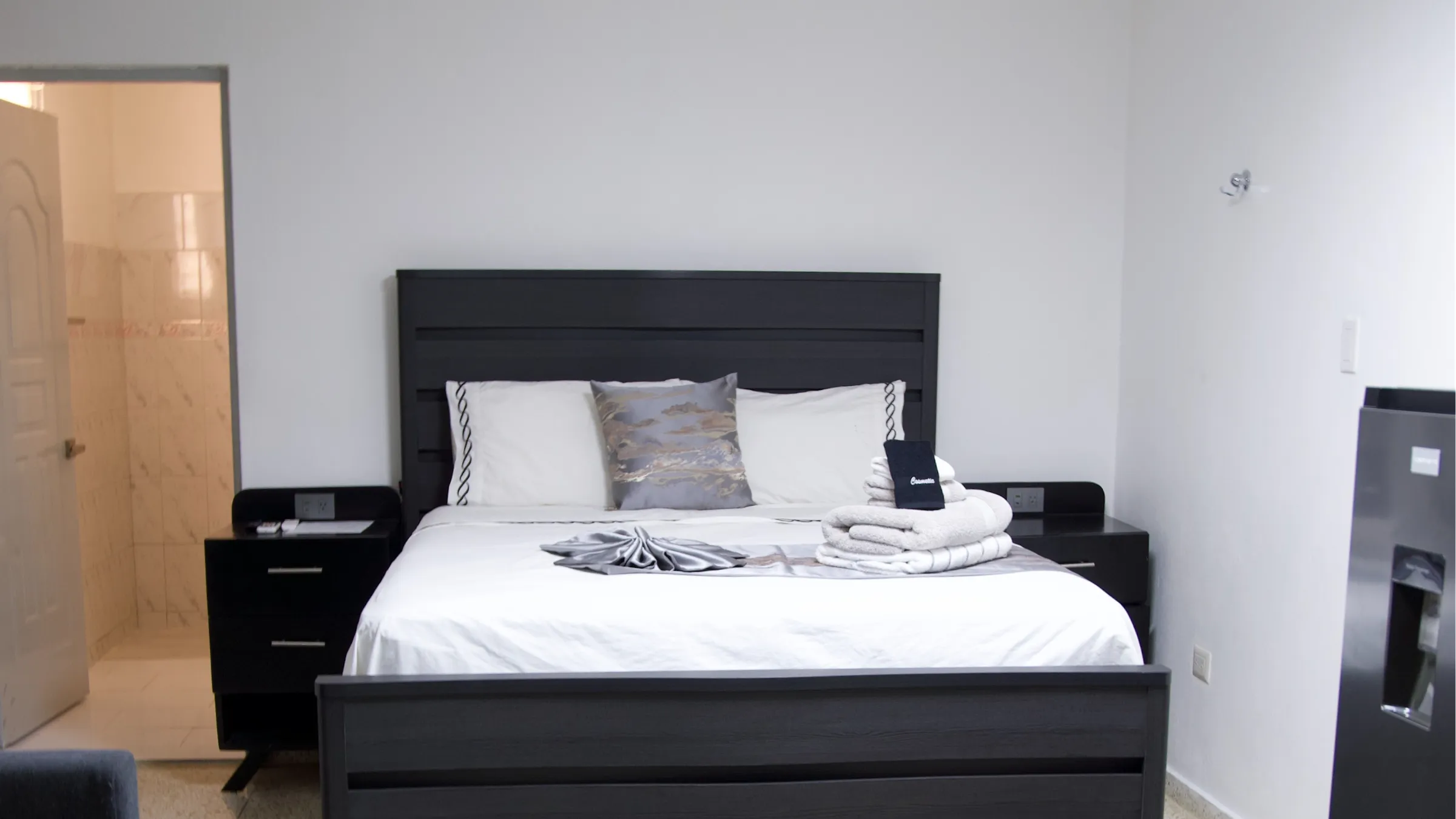 Habitación amplia con cama matrimonial, sofá y nevera
